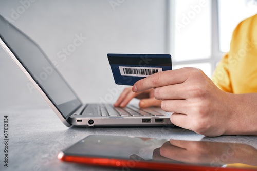 Close up shot of bank card in hand of woman. Shopping online from home