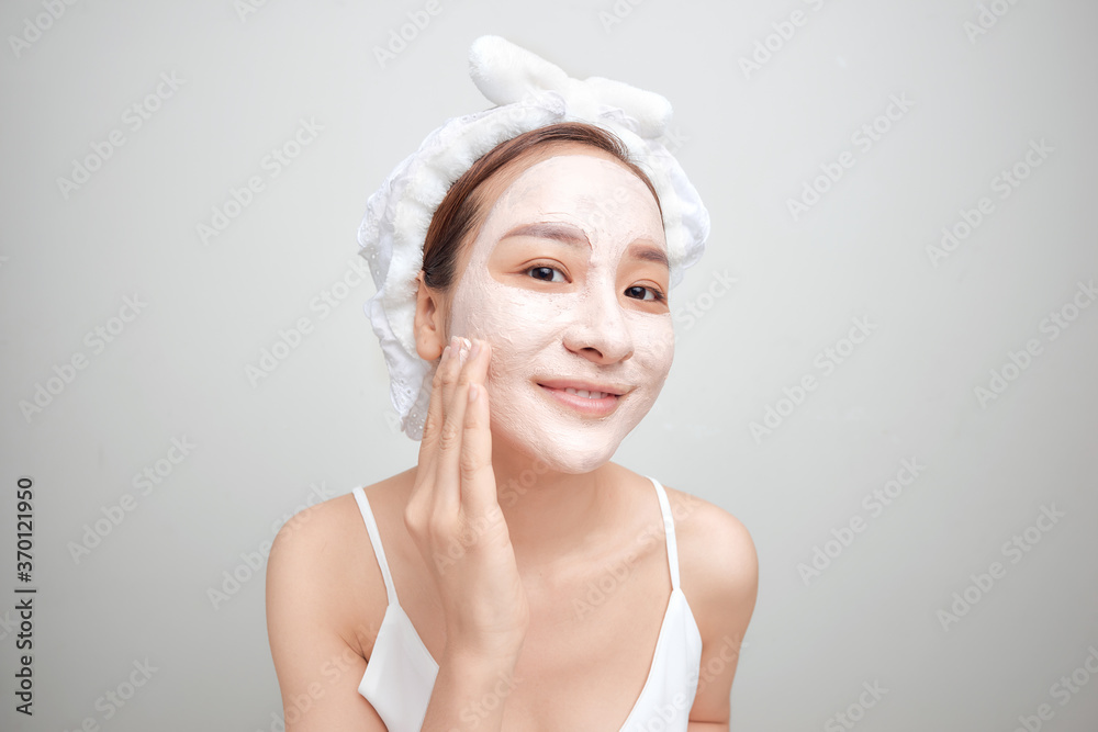 Woman on a white background clean face cream on face towel in hair on head Woman on a white background clean face cream on face towel in hair on head