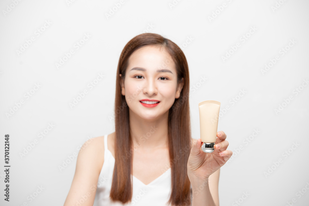 Beauty Youth Skin Care Concept - Beautiful Asian Woman Face Portrait holding and presenting cream tube product. Beauty Youth Skin Care Concept - Beautiful Asian Woman Face Portrait holding and presenting cream tube product.