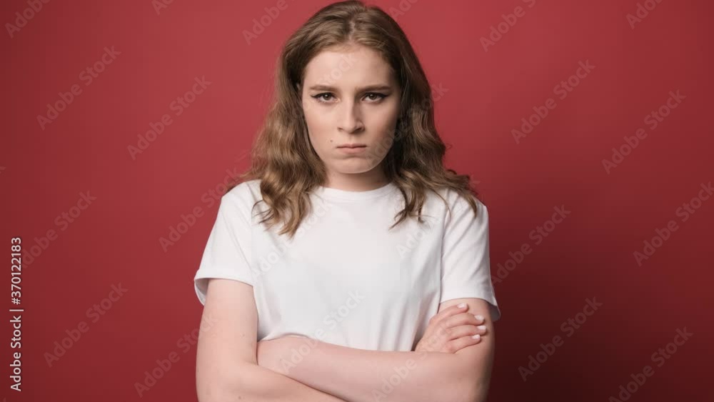 Young Angry and furious woman posing with hands crossed isolated over red background Young Angry and furious woman posing with hands crossed isolated over red background