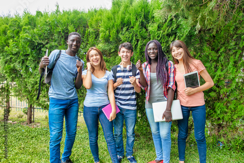 Happy group of mixed races teenagers standing on the grass in the school yard. Back to school concept