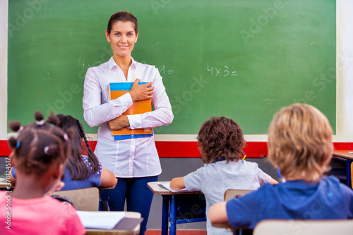 Female teacher explaining school lesson at the chalkboard. Back to school concept