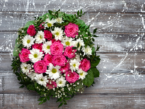Beautiful pink roses and white daisies in a box on a gray wooden background.