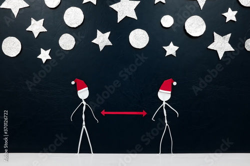 Stick men figure wearing santa hat with red distance marker in between and silver stars and balls ornament background. Safe covid Christmas concept. © sulit.photos