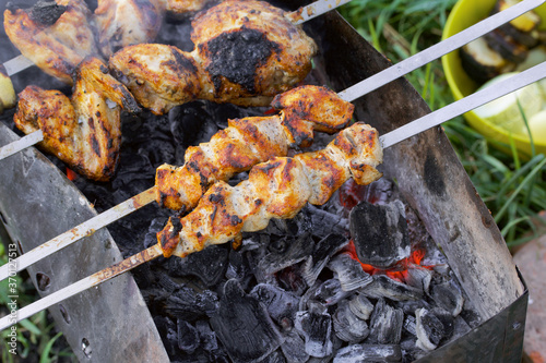 Chicken shish kebab on the grill. You can see fried chicken meat, a barbecue and embers. Taken from above.