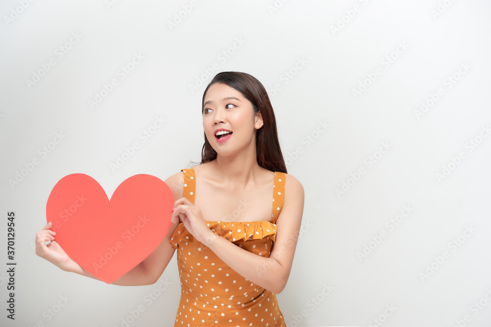 Lifestyle and Holiday Concept - Portrait Young happy woman in polka dot dress holding big red heart paper. Lifestyle and Holiday Concept - Portrait Young happy woman in polka dot dress holding big red heart paper.