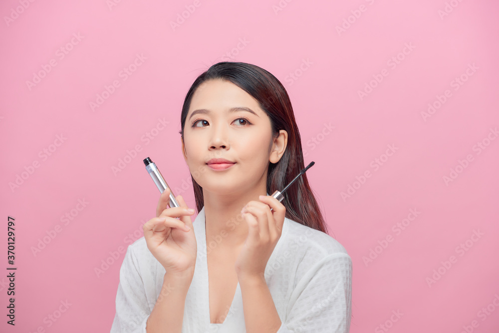 Pretty lady smiling isolated on pink background hold mascara in hands Pretty lady smiling isolated on pink background hold mascara in hands