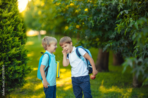 Back to school. Two happy cheerful children, schoolboy boy with backpacks and notebooks in their hands in the park.
