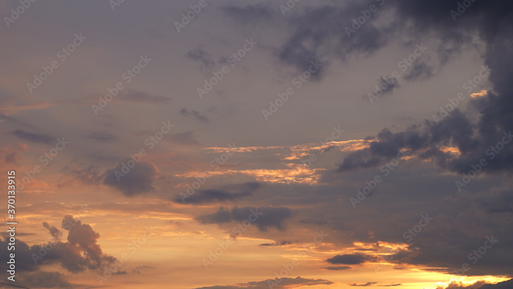 Beautiful evening blue sky at sunset with flaming bright light clouds. A warm summer evening at sunset.