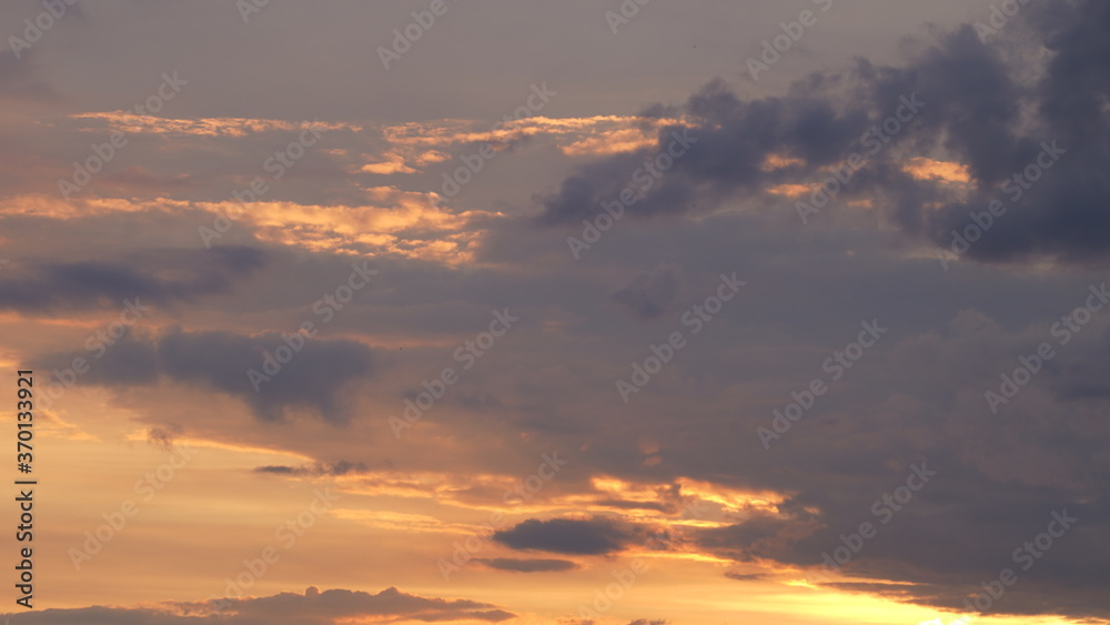 Beautiful evening blue sky at sunset with flaming bright light clouds. A warm summer evening at sunset. Beautiful evening blue sky at sunset with flaming bright light clouds. A warm summer evening at sunset.