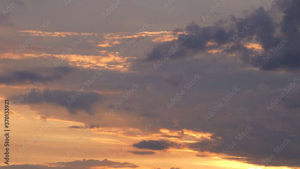 Beautiful evening blue sky at sunset with flaming bright light clouds. A warm summer evening at sunset.