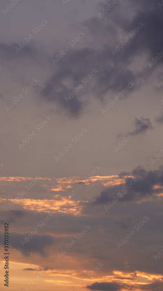 Beautiful evening blue sky at sunset with flaming bright light clouds. A warm summer evening at sunset.