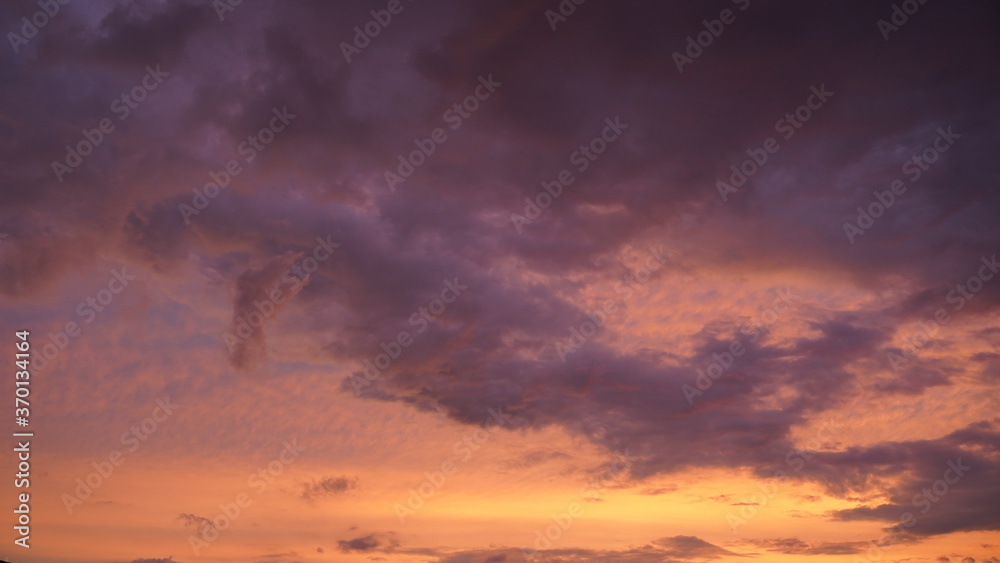 Beautiful evening blue sky at sunset with flaming bright light clouds. A warm summer evening at sunset.