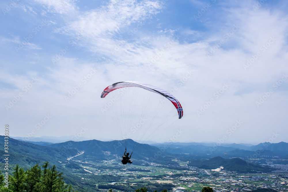 Paraglider flying against the blue sky with colorful wing above the clouds. Paraglider flying against the blue sky with colorful wing above the clouds.
