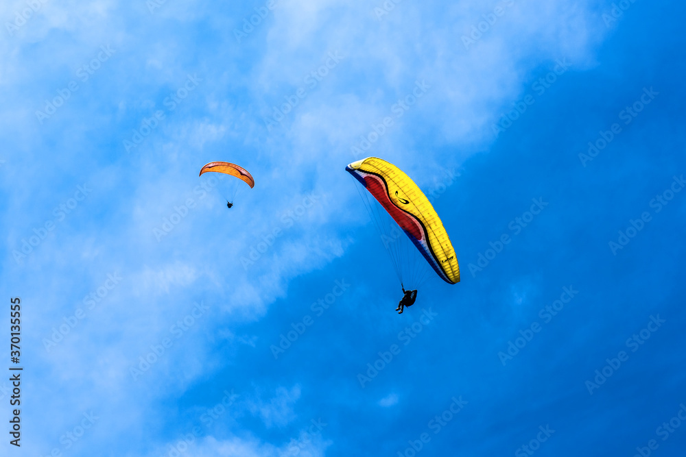 Paraglider flying against the blue sky with colorful wing above the clouds. Paraglider flying against the blue sky with colorful wing above the clouds.