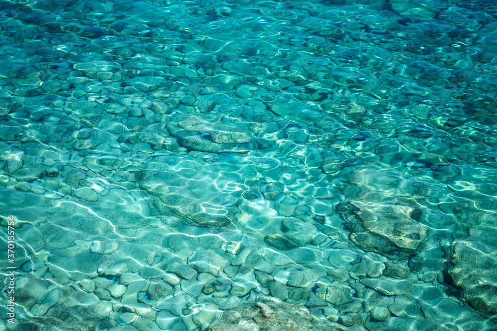 Abstract background and texture, transparent turquoise sea water and stones at the bottom