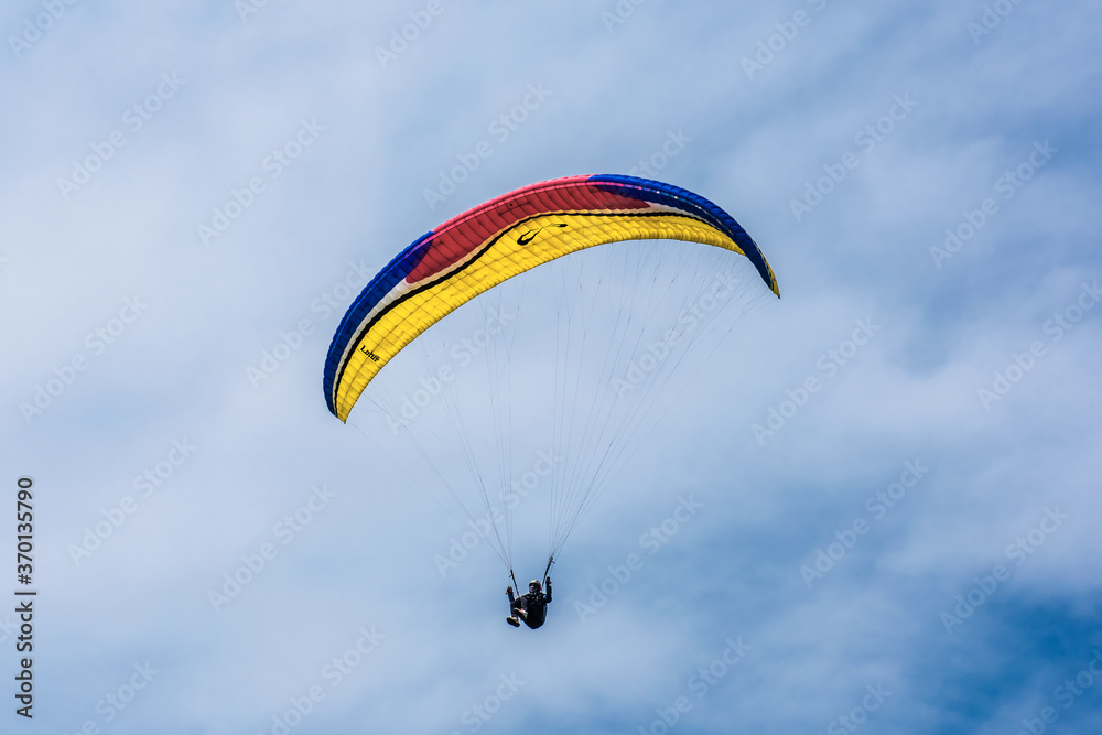 Paraglider flying against the blue sky with colorful wing above the clouds. Paraglider flying against the blue sky with colorful wing above the clouds.