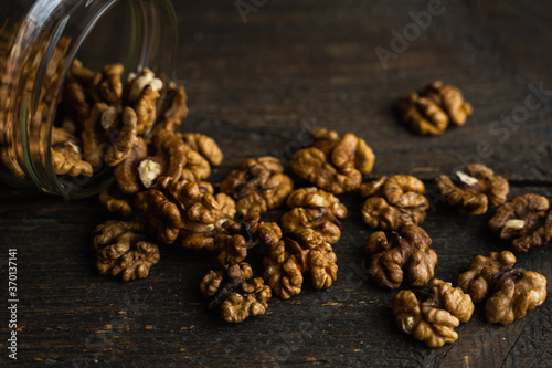 Walnut scattered on the wooden vintage table from a jar. Walnut is a healthy vegetarian protein nutritious food. Walnut kernels and whole walnuts on rustic old wood.