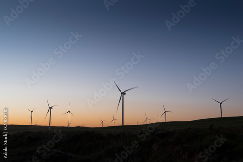 A wind farm during sunset. Turbines generating electricity. Green energy © Herman