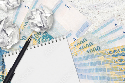 1000 Hungarian forint bills and balls of crumpled paper with blank notepad. Bad ideas or less of inspiration concept. Searching ideas for investment photo