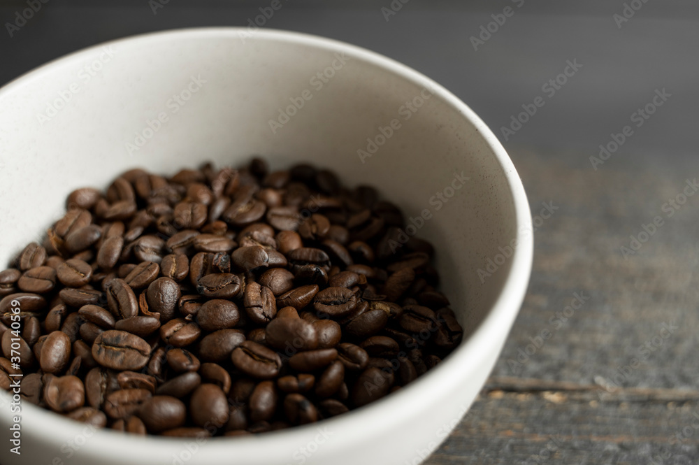 Bowl filled of fresh arabica or robusta coffee beans on a wooden table. Bowl filled of fresh arabica or robusta coffee beans on a wooden table.