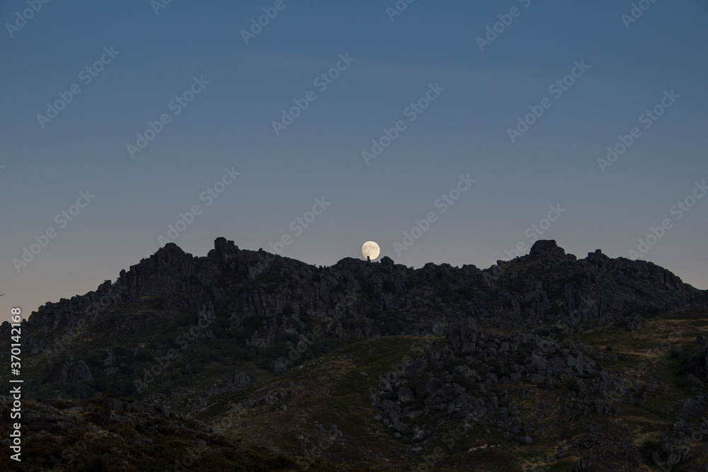 Moon rises behind mountain peaks