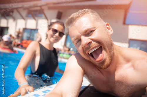 Couple happy caucasian beautiful young woman and man make selfie photo on background swimming pool. Concept travel summer trip
