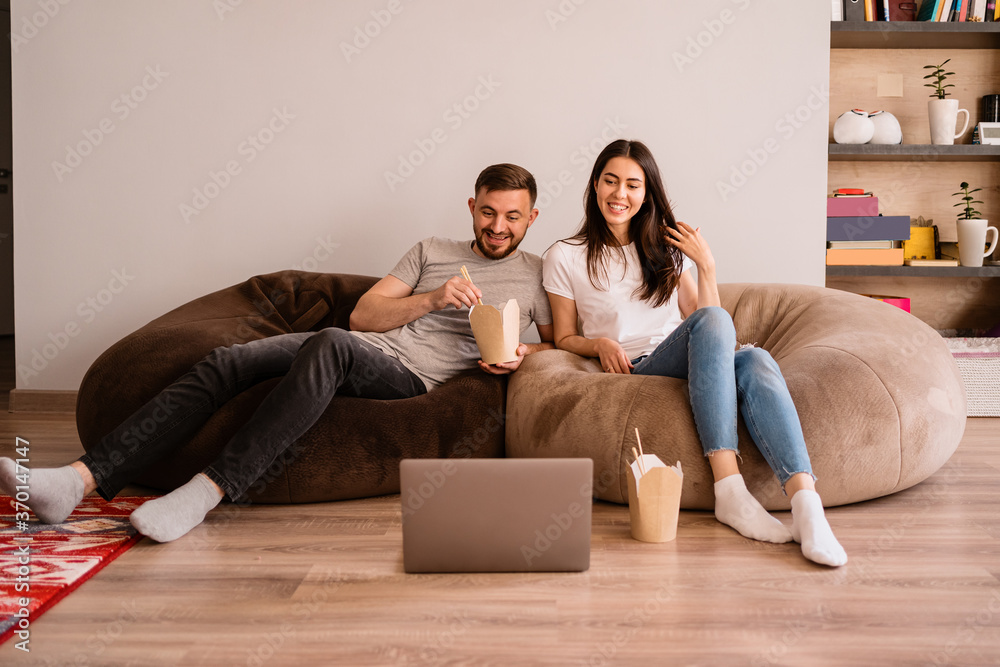 Happy couple enjoys time together while eating together and watching a movie on the laptop Happy couple enjoys time together while eating together and watching a movie on the laptop