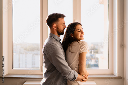 Portrait loving couples enjoying each other company with window in background with sunlight reflection on their faces