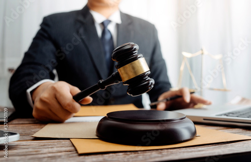 Justice and law concept.Male judge in a courtroom with the gavel, working with, computer and docking keyboard, eyeglasses, on table in morning light