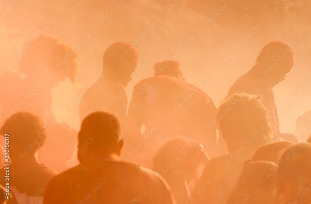 Silhouette of people dancing in colorful smoke at a festival