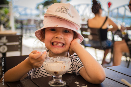 portrait of a little girl in a summer cafe who eats ice cream