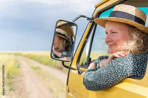 Young blonde woman travelling by campervan though the countryside photo