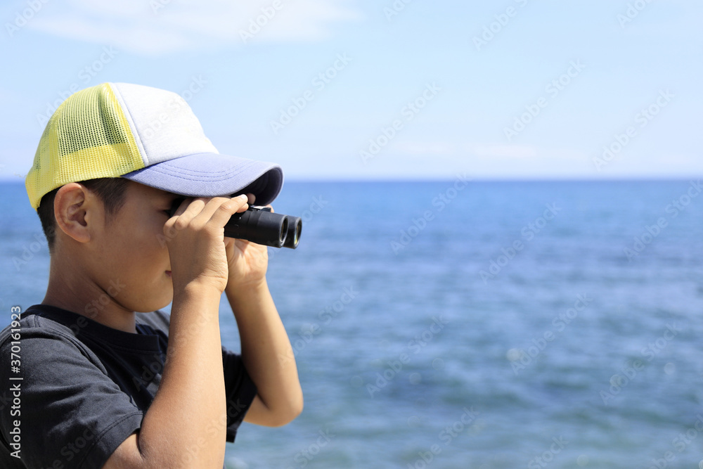 海辺でオペラグラスを使う少年(10歳)