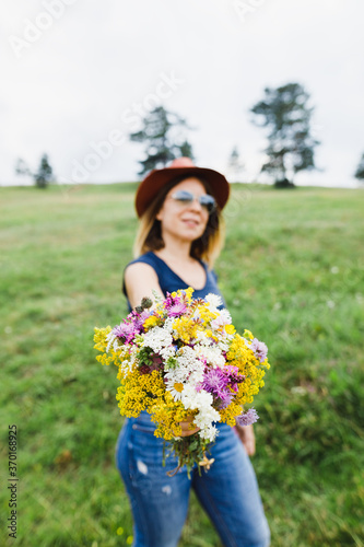 Young woman holding flower bouquet  in the field
