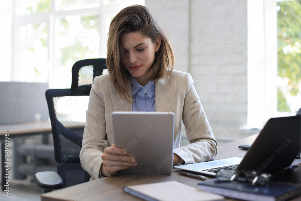 Attractive smiling woman working on a tablet in modern office. Attractive smiling woman working on a tablet in modern office.