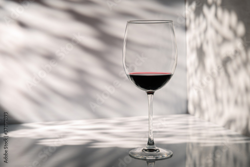 Glass of red wine on a wall background with beautiful light and shadow