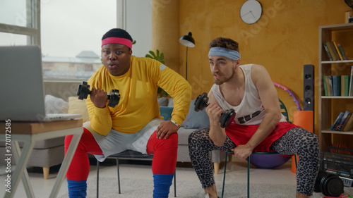 Valokuva Ridiculous weird couple of fitness beginners doing arm exercises on biceps with dumbbels in wrong funny way