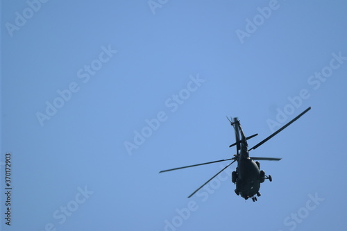 helicopter flies against the blue sky. back view