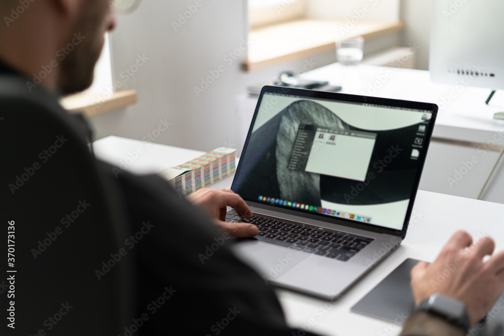 Close up young man with glasses working concentrated at laptop in his modern office Close up young man with glasses working concentrated at laptop in his modern office