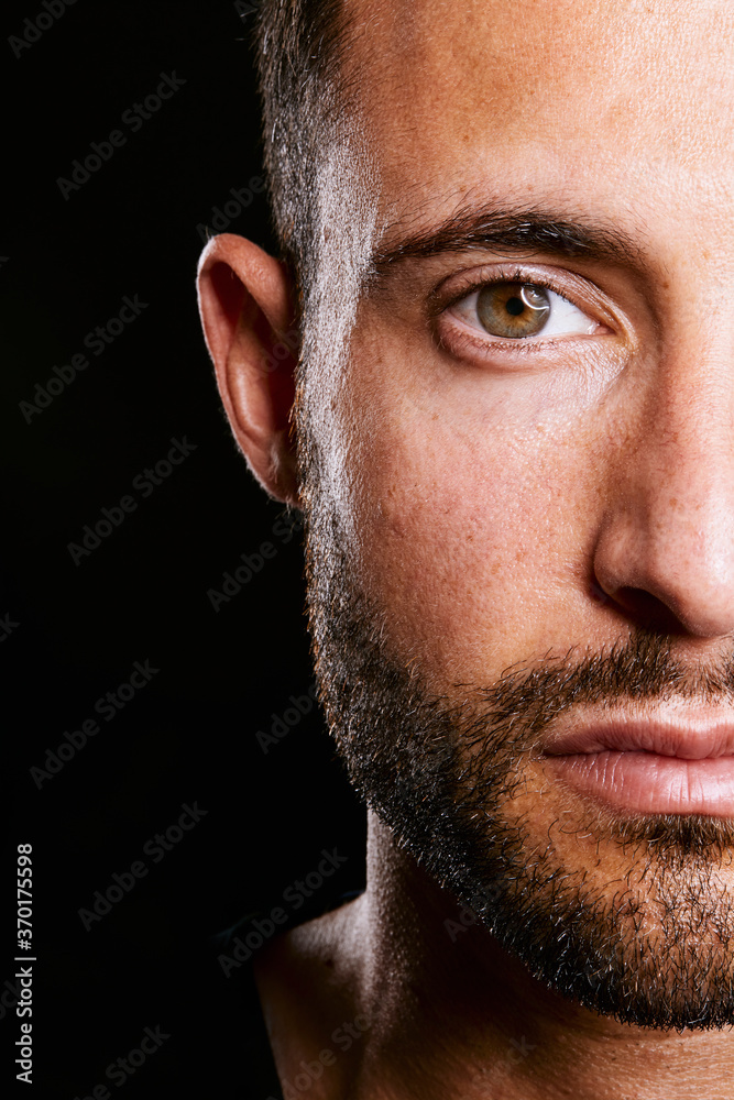 Fototapeta premium gros plan regard sérieux et dramatique d'un homme beau et attirant aux yeux bruns sur fond isolé noir de studio 
