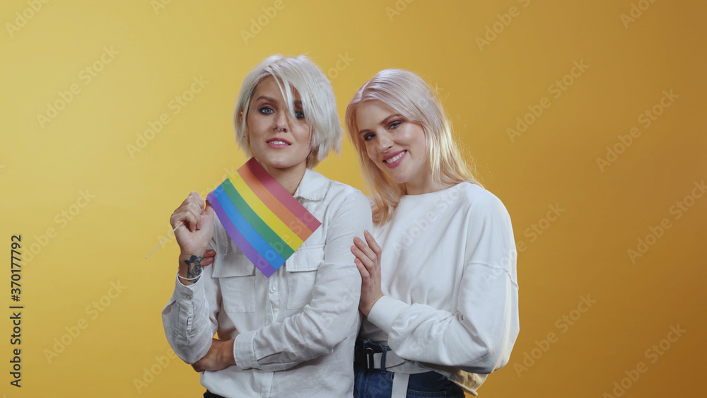 Tender Lgbt female couple family girls tightly hug each other and hold rainbow flag symbolizing love equality and freedom. Lgbt lesbian community. Tender Lgbt female couple family girls tightly hug each other and hold rainbow flag symbolizing love equality and freedom. Lgbt lesbian community.