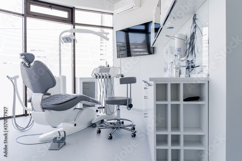 Interior of dental practice room with chair, lamp, display and stomatological tools photo