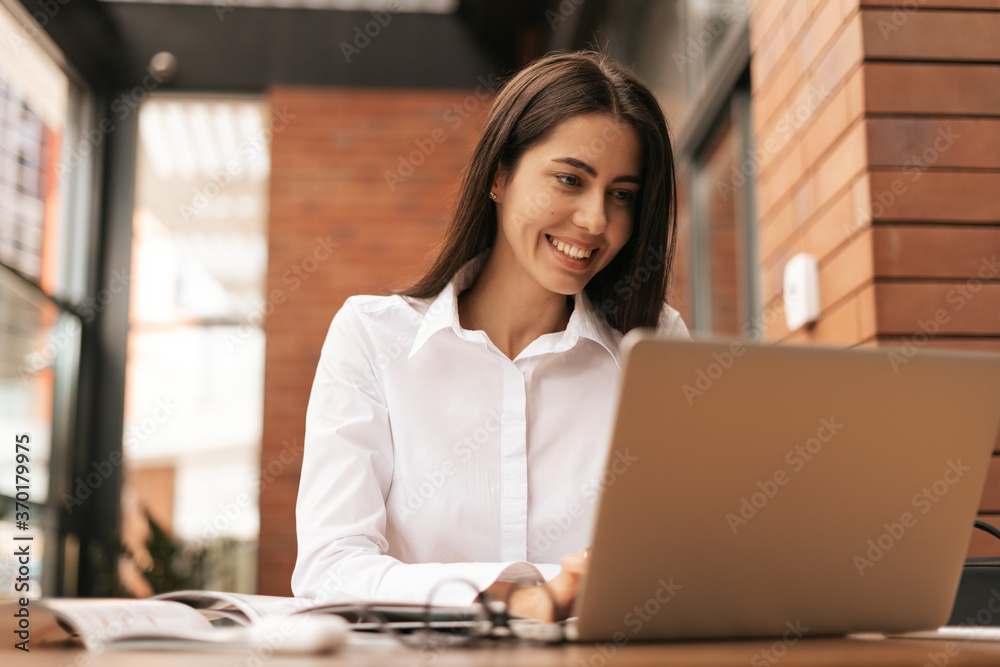 Concentrated at work. Young beautiful woman using her laptop while sitting. Beautiful clever cute charming attractive elegant female owner has online meeting indoors Concentrated at work. Young beautiful woman using her laptop while sitting. Beautiful clever cute charming attractive elegant female owner has online meeting indoors