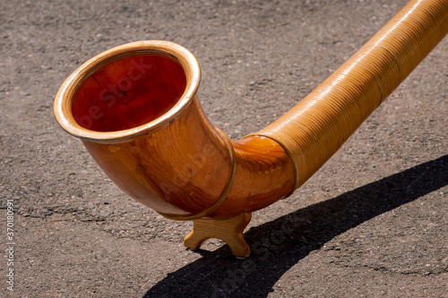 A close up view of the end of wooden Alphorn (Alpenhorn or Alpine horn) on a concrete background. Traditional instrument in Switzerland