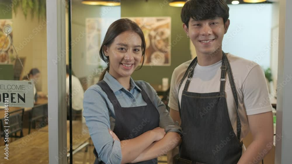 Portrait of Young couple restaurant owner in front of restaurant . waitresses in aprons smiling standing together and looking at camera. Portrait of Young couple restaurant owner in front of restaurant . waitresses in aprons smiling standing together and looking at camera.