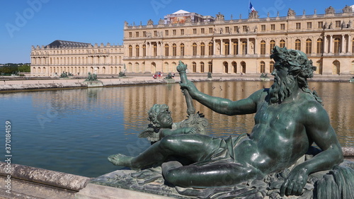 Château de Versailles, avec une statue d'homme, allégorie du fleuve du Rhône, à l’angle d’un des deux bassins du parterre d’eau (France)