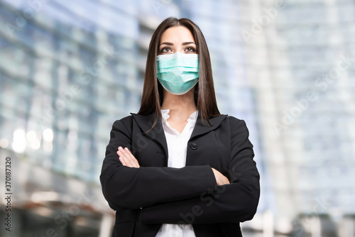 Masked businesswoman in front of her office, coronavirus and work concept