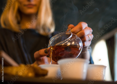 Traditional Chinese Tea Ceremony. Black or Red Tea pouring By a Blonde Caicasian girl into White pial cup on dark Table background