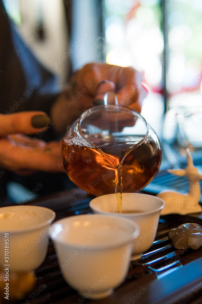 Traditional Chinese Tea Ceremony. Black or Red Tea pouring into White pial cup on dark Table background Traditional Chinese Tea Ceremony. Black or Red Tea pouring into White pial cup on dark Table background